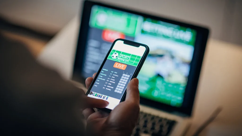 Mature man using mobile app for live betting and online gambling and watching a sports 